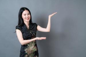 vacker ung asiatisk kvinnakläder kinesisk traditionell klänning med handen presenterar på sidan foto