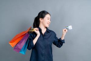 vacker asiatisk kvinna med kassar och visar kreditkort