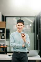 ung attraktiv asiatisk manlig kontor arbetstagare företag leende på kamera i kontor foto