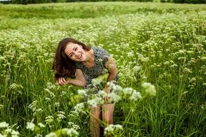 skönhet flicka utomhus njuter natur. skön kvinna Hoppar på sommar fält med blomning vild blommor, Sol ljus. fri Lycklig kvinna. foto