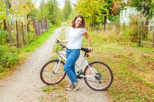 ung kvinna ridning cykel i sommar stad parkera utomhus. aktiva människor. hipster flicka koppla av och ryttare cykel. cykling till arbete på sommar dag. cykel och ekologi livsstil begrepp. foto