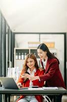 två asiatisk affärskvinna diskutera investering projekt arbetssätt och planera strategi med läsplatta bärbar dator dator i kontor. foto