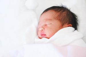 nyfött barn sova i vit filt.