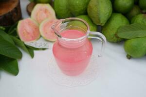 färsk guava juice i en glas och färsk guava frukt. foto