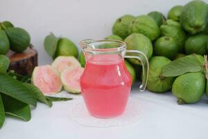 färsk guava juice i en glas och färsk guava frukt. foto
