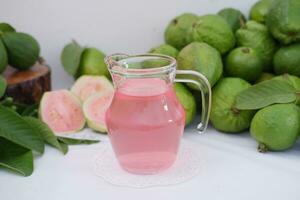 färsk guava juice i en glas och färsk guava frukt. foto