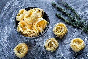 rå tagliatelle nido på de mjöldammad svart trä- bakgrund foto