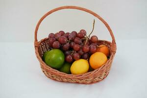 frukt i en korg på en vit bakgrund. orange, druva, citron. foto