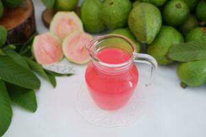 färsk guava juice i en glas och färsk guava frukt. foto