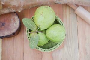guava frukt i korg på trä tabell bakgrund, friska mat foto
