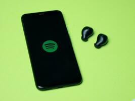 väst java, indonesien - juli 27: e 2023 - Spotify Ansökan på smartphones och trådlös hörlurar. för strömning musik innehåll foto