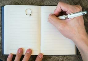 hand skrivning vit penna anteckningsbok med diamant ringa foto