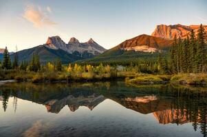 landskap av tre systrar bergen reflexion på damm på soluppgång i höst på banff nationell parkera foto