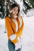 tonåring blond i en gul Tröja utanför i vinter. en Tonårs flicka på en promenad i vinter- kläder i en snöig skog foto