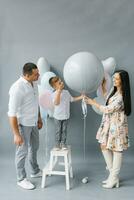 kön avslöja fest. eleganta skön familj med en bebis pop- en ballong till hitta ut de kön av de ofödd barn i de familj foto