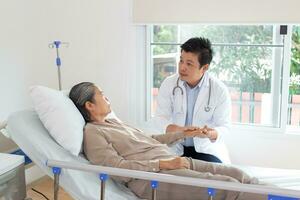manlig läkare diskuterar över medicinsk spela in med senior kvinna i sjukhus. foto