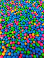 färgad plast bollar är spridd. massor av Flerfärgad roligt ballonger.många färgrik plast bollar i en ungar' bollhav på en lekplats. stänga upp mönster foto