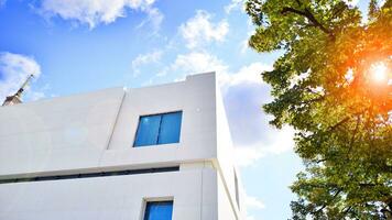 modern vit betong byggnad väggar mot blå himmel. eco arkitektur. grön träd och betong kontor byggnad. de harmoni av natur och modernitet. foto