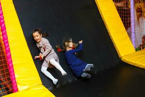 barn Hoppar på färgrik lekplats trampolin. barn hoppa i uppblåsbar studsa slott på dagis födelsedag fest aktivitet och spela Centrum för ung barn. liten flicka spelar utomhus i sommar. foto