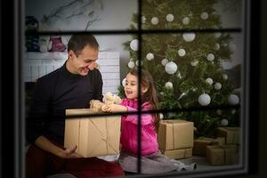 Lycklig ung far och hans dotter på Hem med jul träd fönster foto