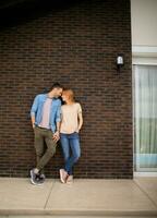leende ung par i kärlek i främre av hus tegel vägg foto