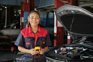 ett svart kvinna professionell bil- mekanisk arbetstagare checkar ett ev bil batteri och hybrid motor på en underhåll garage, expert- elektrisk fordon service, och fixering yrken bil industri. foto