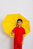 liten pojke mode en leende barn innehav en gul paraply i en röd kinesisk klänning. kinesisk ny år, kinesisk ny år foto