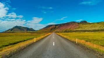 panorama- över en asfalterad väg och isländsk färgrik och vild landskap med fjordar och hav på sommar tid, väst island foto