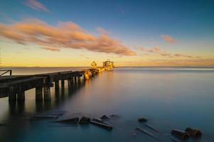 den gamla bron i havet på stranden vid soluppgången foto