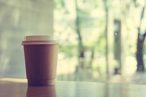 varmt lattekaffe i papperskopp på bord i kafé foto