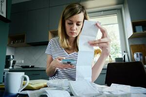kvinna beräknande betalning räkningen i kök foto