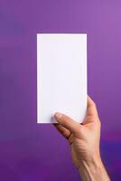 en mänsklig hand innehav en tom ark av vit papper eller kort isolerat på lila bakgrund. ai genererad foto
