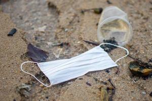 använd mask under covid 19 kastades på sandstranden. ämnet är begravd. foto