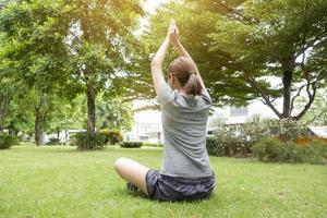 närbild av kvinna som gör yoga i grön trädgård foto