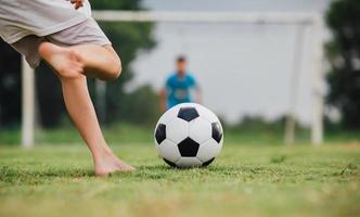 action sport utomhus av en grupp barn som har kul att spela fotboll fotboll för träning i gemenskapens lantliga område under skymningssolnedgången. foto