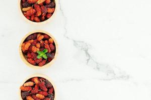 svart mullbärsfrukt i skål foto