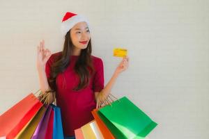 porträtt vackra unga asiatiska kvinnor bär jul santa hatt med shopping väska foto