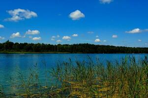 sommar idyllisk landskap med en sjö under en blå himmel på en värma solig dag foto