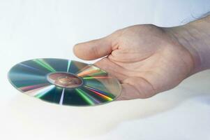 CD disk i manlig hand på vit bakgrund foto
