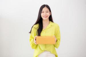 ung asiatisk kvinna som ler och håller pappkartongen hemma, glad kvinnlig bärande paketlåda ger, present och gåva, förpackning för leverans, online-butik och servicekoncept.