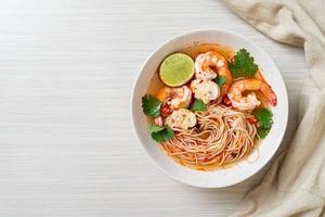 nudlar med kryddig soppa och räkor i vit skål, eller tom yum kung - asiatisk matstil foto