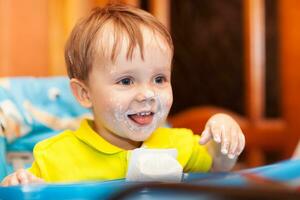 Lycklig barn smutsig med grädde yoghurt foto