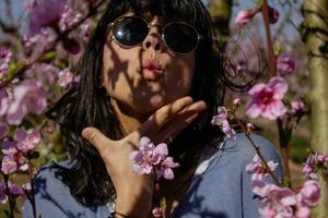 kvinna bland de Söt rosa persika träd blommor. foto