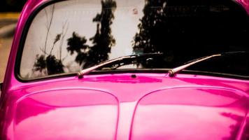 närbild på bakre vindrutetorkarm och blad på solblekta rosa vintage motorfordon foto