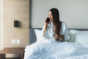 stående vackra unga asiatiska kvinnor lyckligt leende med kaffe och mobiltelefon foto