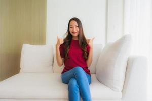 stående vackra unga asiatiska kvinnor lyckligt leende sitta på soffan