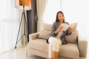 stående vackra unga asiatiska kvinnor som läser bok och sitter på soffstol
