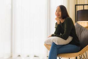 stående vackra unga asiatiska kvinnor lyckligt leende koppla av sittande på soffstol foto