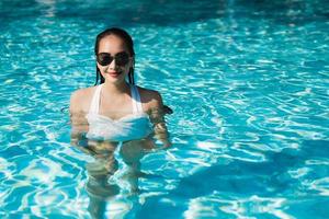 vacker ung asiatisk kvinna glad och ler i poolen för att koppla av resor och semester foto