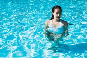 vacker ung asiatisk kvinna glad och ler i poolen för att koppla av resor och semester foto